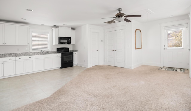 kitchen with sink, black appliances, light carpet, ceiling fan, and white cabinets