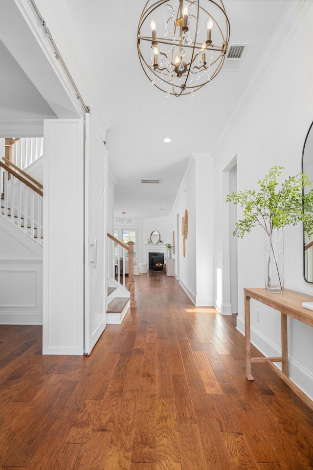 foyer entrance featuring a notable chandelier, dark wood-type flooring, and ornamental molding