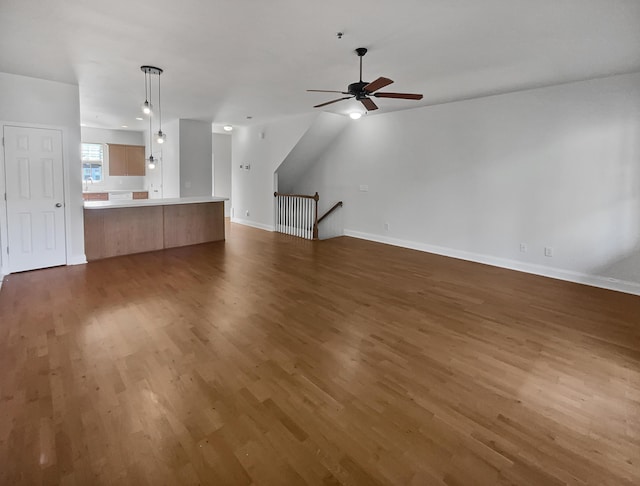 unfurnished living room featuring ceiling fan and dark wood-type flooring