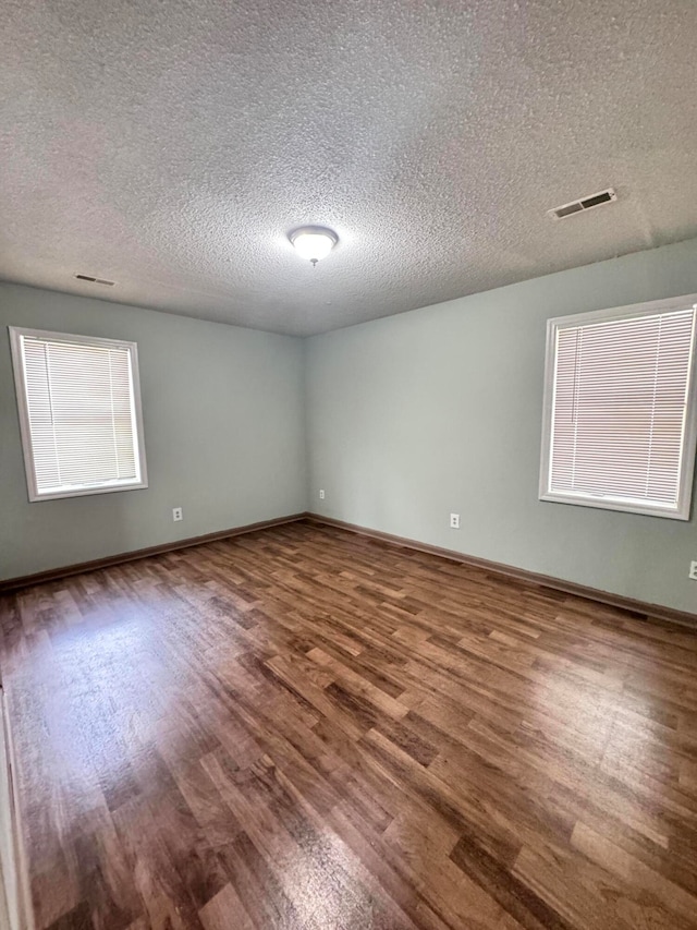 unfurnished room with hardwood / wood-style floors and a textured ceiling