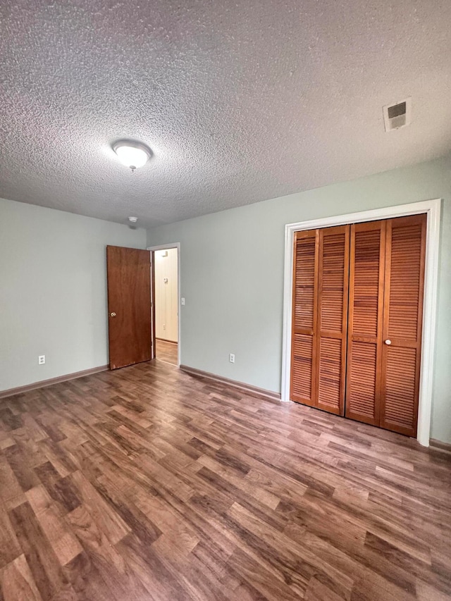 unfurnished bedroom with a textured ceiling, a closet, and hardwood / wood-style flooring