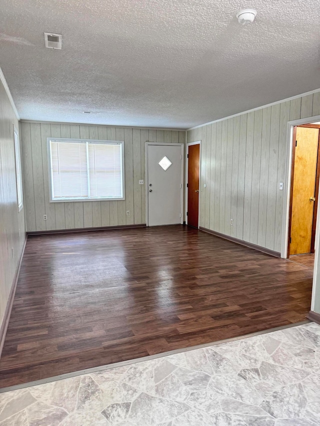 foyer with wood walls, a textured ceiling, and dark hardwood / wood-style floors