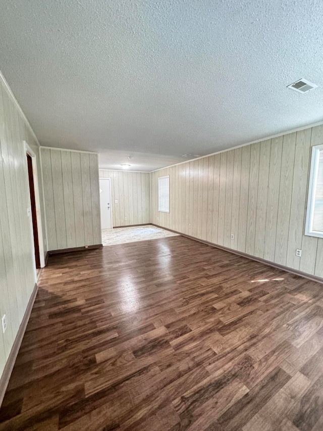 interior space featuring wood walls, a textured ceiling, and hardwood / wood-style flooring