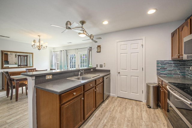 kitchen featuring appliances with stainless steel finishes, decorative light fixtures, sink, kitchen peninsula, and light wood-type flooring