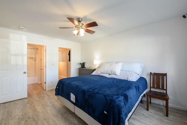 bedroom with a walk in closet, ensuite bathroom, ceiling fan, and light wood-type flooring