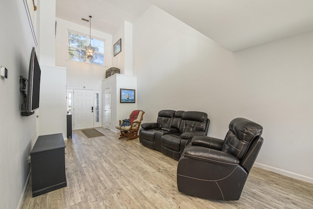 living room with a towering ceiling, wood-type flooring, and a notable chandelier