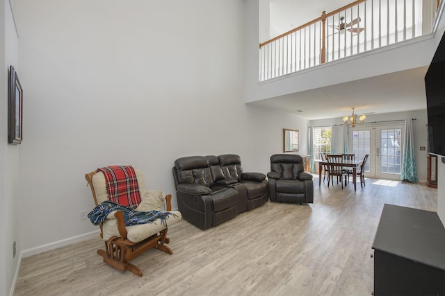 living room with a chandelier, light hardwood / wood-style flooring, and a high ceiling