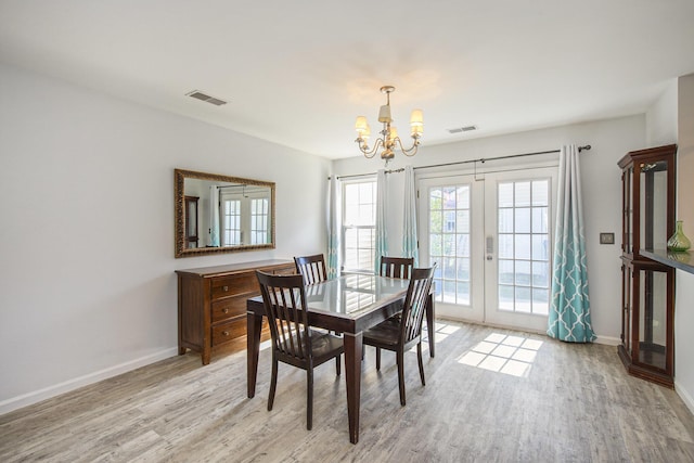 dining area with french doors, a notable chandelier, and light wood-type flooring