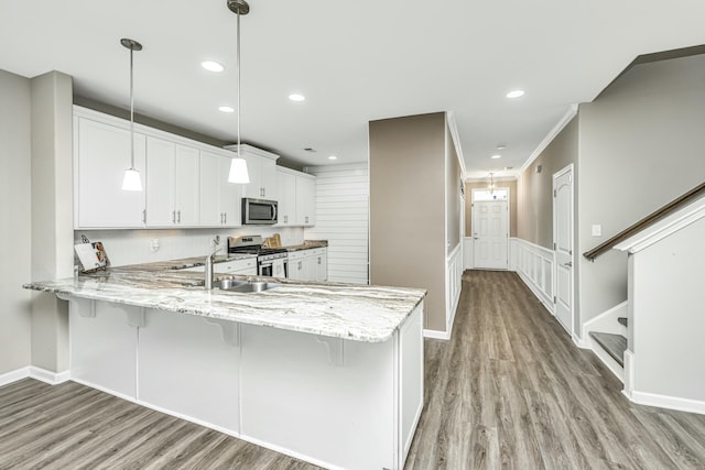 kitchen featuring crown molding, white cabinets, kitchen peninsula, pendant lighting, and stainless steel appliances