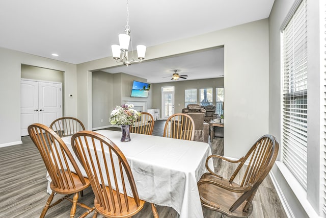 dining area with hardwood / wood-style flooring and ceiling fan with notable chandelier