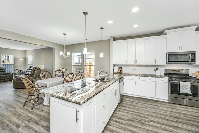 kitchen featuring kitchen peninsula, hanging light fixtures, sink, white cabinetry, and stainless steel appliances