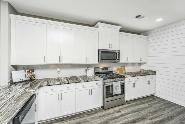 kitchen featuring white cabinets, dark hardwood / wood-style flooring, dark stone counters, and stainless steel appliances