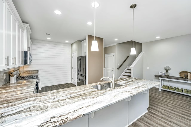 kitchen with hanging light fixtures, appliances with stainless steel finishes, sink, white cabinets, and a breakfast bar