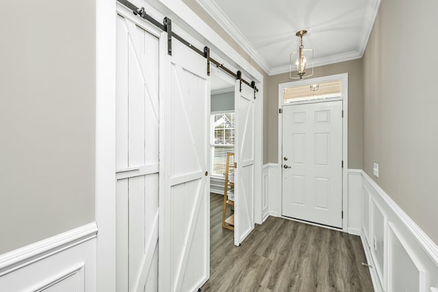 doorway featuring hardwood / wood-style floors, ornamental molding, and a barn door