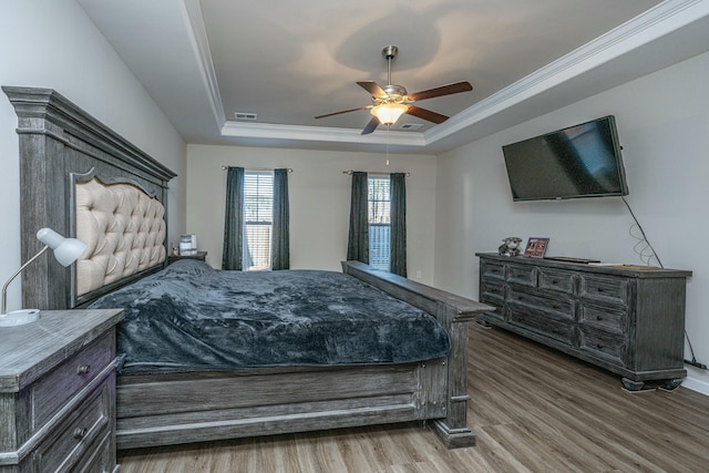 bedroom featuring ceiling fan, crown molding, hardwood / wood-style flooring, and a tray ceiling