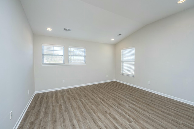 unfurnished room with vaulted ceiling, a healthy amount of sunlight, and light hardwood / wood-style floors