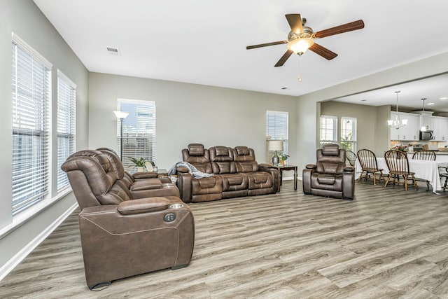 living room featuring hardwood / wood-style flooring, ceiling fan with notable chandelier, and a healthy amount of sunlight