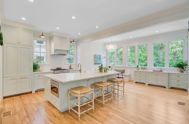 62 Eastlake Rd, Mount Pleasant, SC 29464 - kitchen featuring a kitchen bar, light wood-type flooring, light countertops, stainless steel microwave, and backsplash