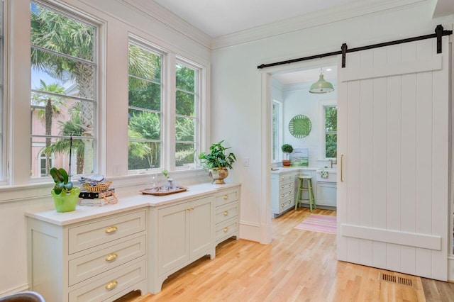 62 Eastlake Rd, Mount Pleasant, SC 29464 - kitchen with a barn door, light countertops, light wood-style flooring, healthy amount of natural light, and crown molding