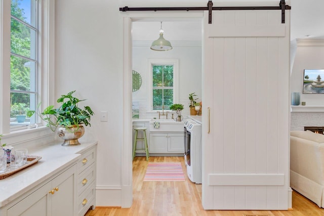 62 Eastlake Rd, Mount Pleasant, SC 29464 - washroom featuring a barn door, light wood finished floors, and washer and dryer