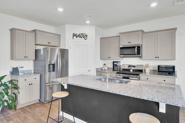 kitchen featuring a kitchen breakfast bar, visible vents, appliances with stainless steel finishes, and gray cabinetry