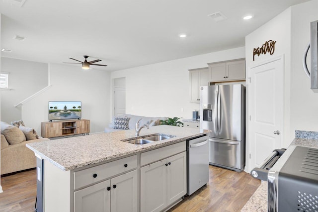 kitchen featuring ceiling fan, open floor plan, light wood-type flooring, stainless steel appliances, and a sink