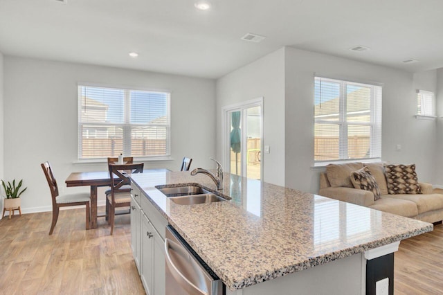 kitchen featuring a sink, white cabinetry, stainless steel dishwasher, and light wood finished floors