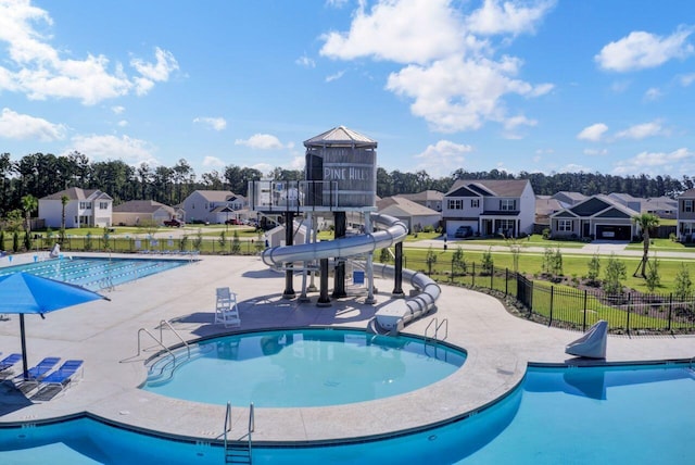 pool featuring a patio area, fence, a residential view, and a water slide