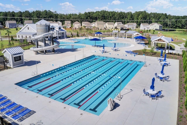 pool featuring a patio area, a residential view, a water slide, and fence