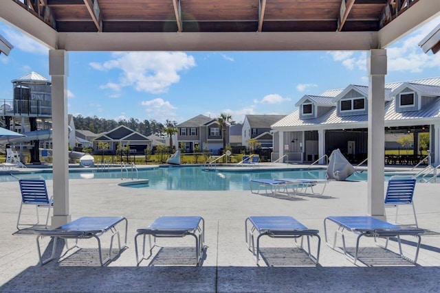 community pool with a residential view, a patio, and a water slide