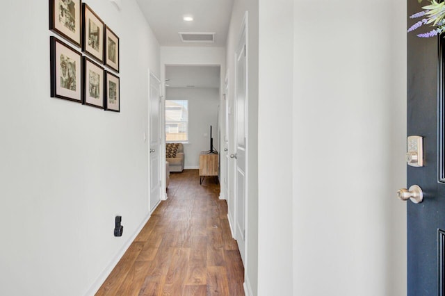 hall with visible vents, baseboards, and wood finished floors