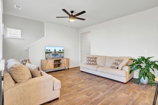 living room with baseboards, visible vents, a ceiling fan, and light wood-style floors