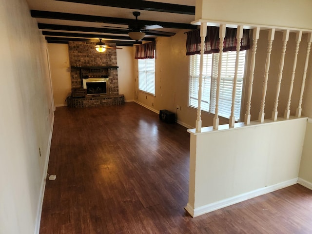 unfurnished living room featuring a ceiling fan, a fireplace, beamed ceiling, and wood finished floors