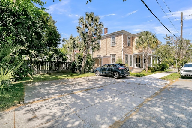 view of home's exterior with a chimney and fence