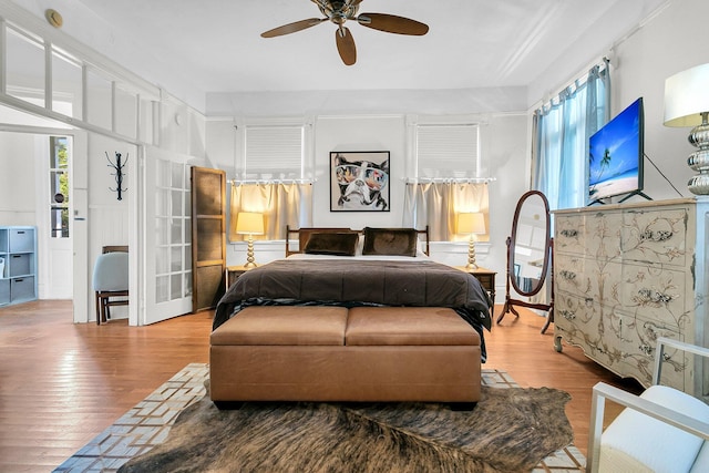 bedroom with a ceiling fan, wood finished floors, and multiple windows
