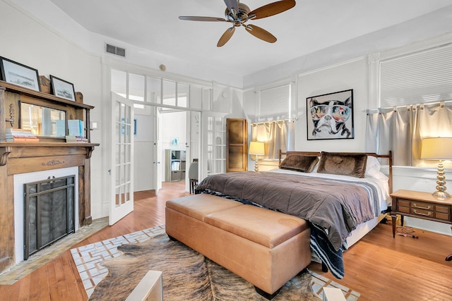 bedroom with a fireplace with flush hearth, visible vents, french doors, and wood finished floors