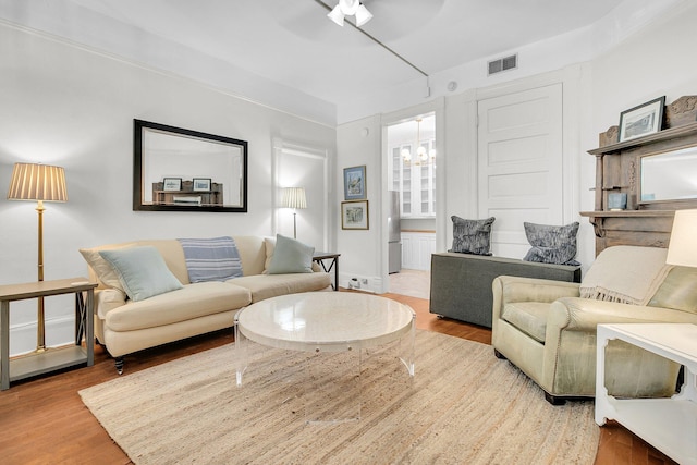 living room with ceiling fan with notable chandelier, wood finished floors, and visible vents