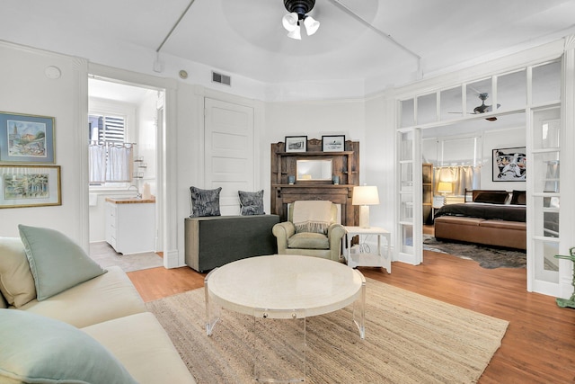 living room with light wood-style flooring, a ceiling fan, and visible vents