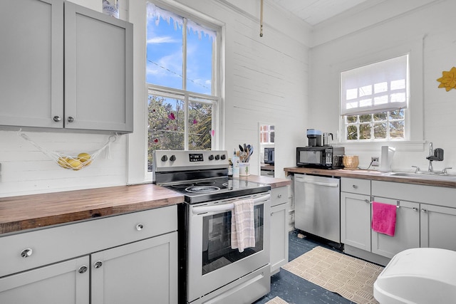 kitchen with butcher block countertops, a sink, and appliances with stainless steel finishes