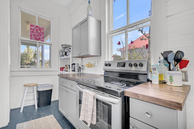 kitchen with butcher block countertops, a healthy amount of sunlight, dark floors, and stainless steel electric range
