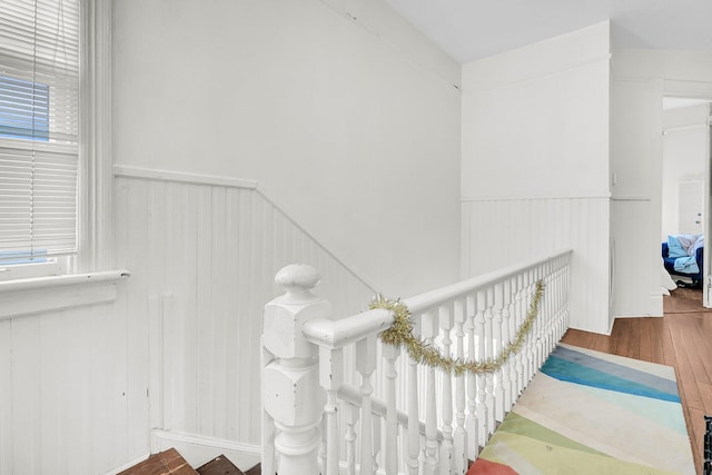 stairs featuring wainscoting and wood finished floors