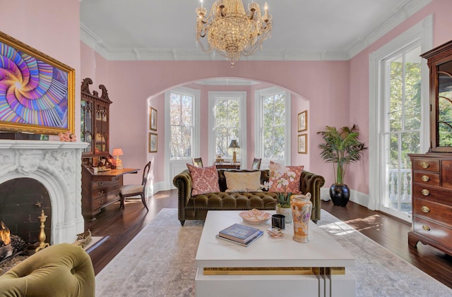 living room featuring ornamental molding, dark wood-type flooring, a high end fireplace, and a chandelier