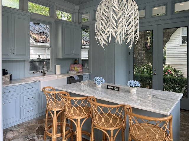 kitchen featuring a breakfast bar, light stone countertops, and sink