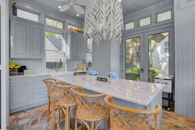 kitchen featuring a breakfast bar, plenty of natural light, gray cabinets, and french doors