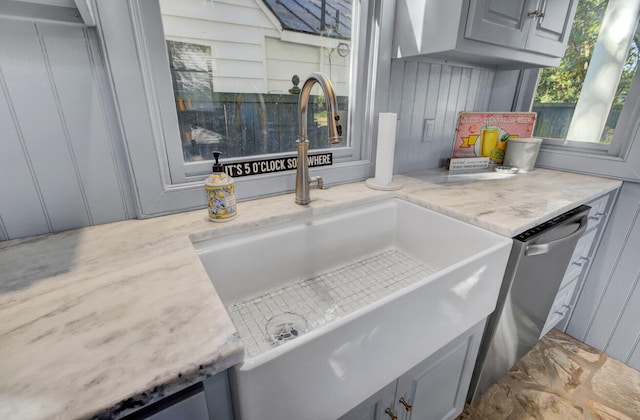 interior details with gray cabinets, light stone countertops, sink, and stainless steel dishwasher