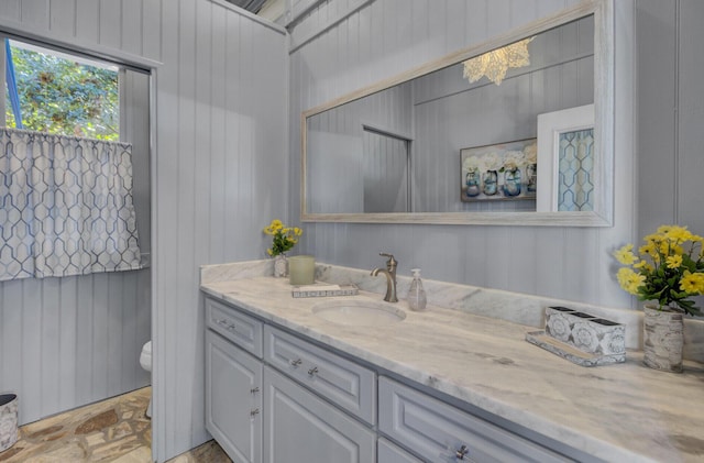 bathroom featuring vanity, toilet, and wood walls