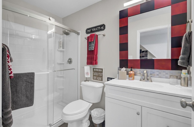 bathroom with vanity, toilet, a shower with door, and tasteful backsplash