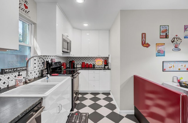 kitchen featuring decorative backsplash, white cabinets, and stainless steel appliances