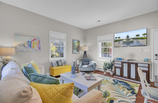 living room with hardwood / wood-style floors, baseboard heating, and a wealth of natural light