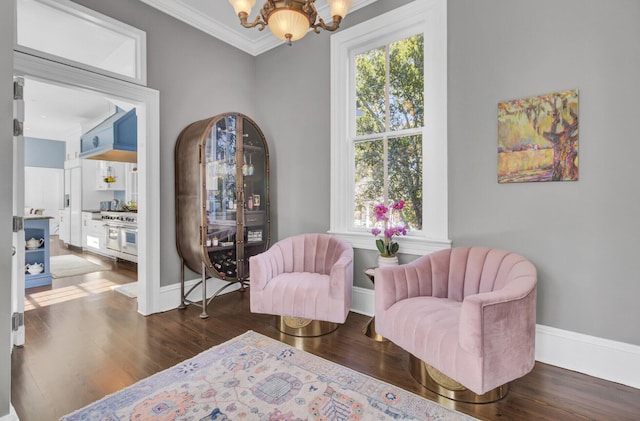 living area with dark hardwood / wood-style floors, an inviting chandelier, and crown molding